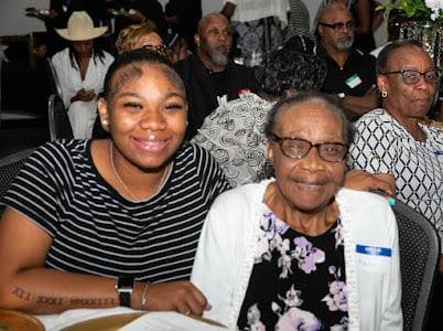 A young guest and an older guest pose together at the celebration.