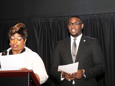 Two presenters read from the podium.