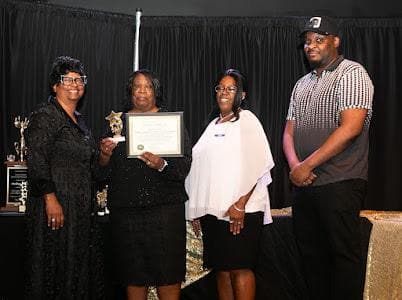 An honoree receives a certificate of recognition on stage.