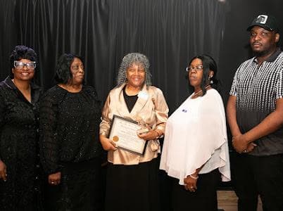 An honoree holds a certificate of recognition beside members of the Miracle Mission team.