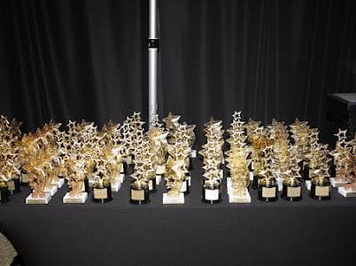 A table filled with gold trophies prepared for honorees.