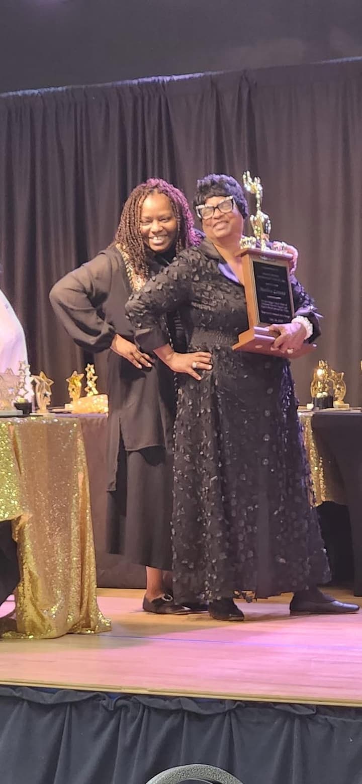 Two women pose together on stage.