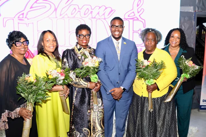 Honorees holding bouquets pose with guests at the award celebration.