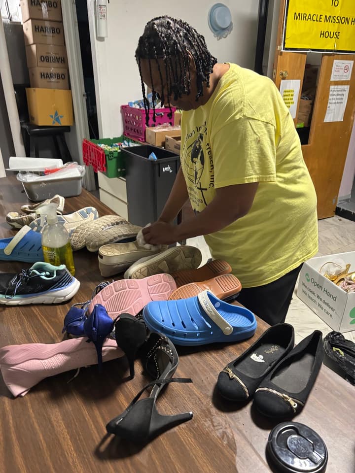 A volunteer arranges donated shoes on a table.