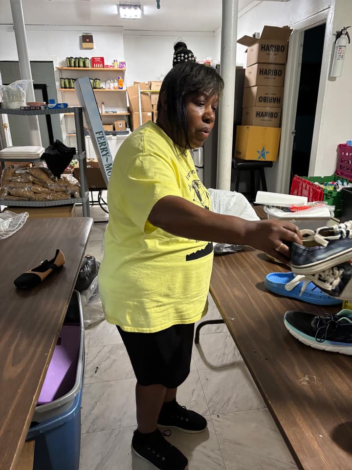 A volunteer in a yellow T-shirt sorts donations at a work table.