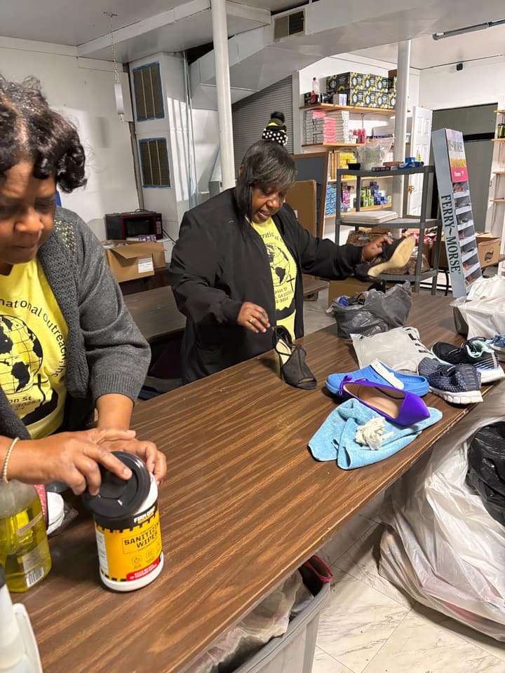 Volunteers sort and clean donated shoes at a long table.